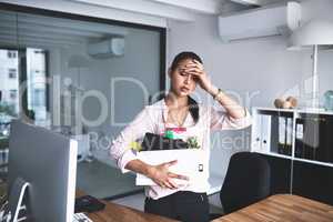 Its the most stressful thing that could happen to anyone. Shot of an unhappy businesswoman holding her box of belongings after getting fired from her job.