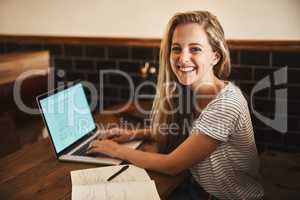 This is my favorite study spot. Portrait of a happy young student using her laptop to study at a cafe table.