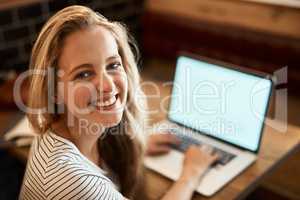 Putting in an A+ effort. Portrait of a happy young student using her laptop to study at a cafe table.