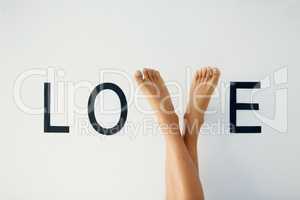 Stand on love. Closeup shot of an unrecognizable persons crossed legs with his feet making up the letter V in the word LOVE.