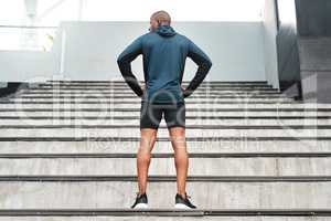 On the count of three. Rearview shot of an unrecognizable young athlete standing akimbo before running up a flight of stairs during a workout.
