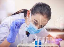 She wont stop until she finds a cure. Shot of a young scientist transferring liquid from a pipette to a test tube in a laboratory.