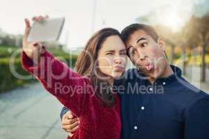 I found my soulmate in silliness. Shot of a young couple making funny faces while taking a selfie outdoors.