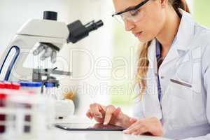 Logging her findings online. Cropped shot of a young female scientist recording her findings on a digital tablet.