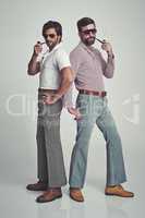 We know we're groovy. Studio shot of two men standing together while wearing retro 70s wear and striking a pose.