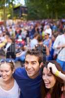 Friends at the festival. A group of smiling friends enjoying a music festival with crowd in the background.