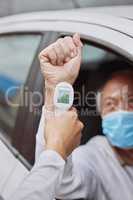 Let's check your temperature. Shot of an unrecognizable healthcare worker taking a patient's temperature at a drive through vaccination site.