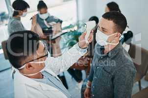 It all starts with a fever. Shot of a young man getting his temperature taken with an infrared thermometer by a healthcare worker during an outbreak.
