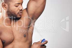 Grooming is vital for any gentleman. Studio shot of a handsome young man spraying deodorant on his armpit against a white background.