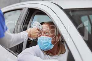 I'm going to take your temperature. Shot of a senior man getting his temperature taken at a drive through vaccination site.