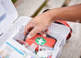 Everything he needs to treat your injuries. High angle shot of an unrecognizable male paramedic looking in his first aid kit while standing outside.