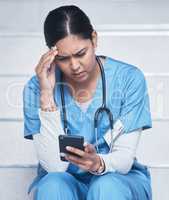 Looks like Im booked for another shift. Shot of a female nurse looking upset while using her cellphone.