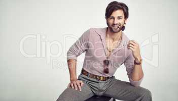 Groovy cool. A young man with 70s style sitting in the studio and smoking a pipe.