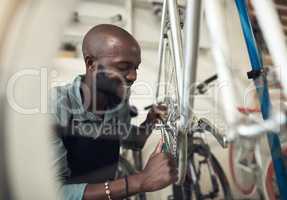 Bikes are my passion. Shot of a handsome young man crouching in his shop and repairing a bicycle wheel.