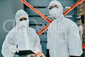 Working together to save the world. Shot of two healthcare workers wearing hazmat suits working together to control an outbreak.