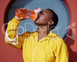 Libation of hydration, quenching the Goddess in you. Shot of a young woman drinking water after her workout against an urban background.