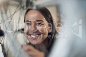 This looks as good as new. Shot of an attractive young woman crouching alone in her shop and repairing a bicycle wheel.