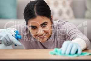 Mrs Dust Buster. Shot of a woman using a spray bottle and cloth while cleaning a table.