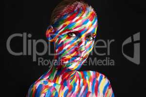 Eye catching, eye popping colorful beauty. Studio shot of a young woman posing with brightly colored paint on her face against a black background.