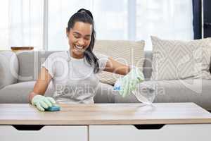 I never miss a spot. Shot of an attractive young woman using a sponge and spray bottle to clean the surfaces at home.