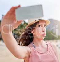 Embracing a little holiday silliness. Shot of a happy young woman taking a selfie with her phone on a tropical beach.