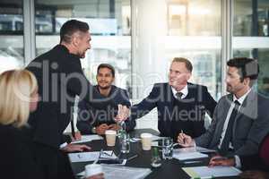 I'm glad everyone agrees. Shot of two cheerful businessmen shaking hands in agreement in a boardroom at the office.