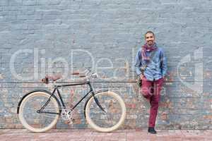 Why drive when you can cycle. Portrait of a young man posing with his bicycle against a grey wall in the city.