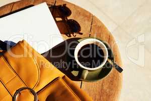 This arrangement will make a great blog post. High angle shot of a cup of coffee and a bag neatly arranged on a coffee table during the day.