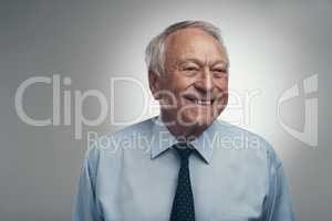 Happiness is never something that goes out of style. Shot of a senior businessman standing alone against a grey background in the studio during the day.