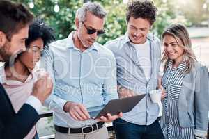 Getting the team on the same page. Shot of a group of businesspeople working together on a laptop outdoors.