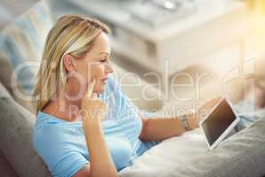 Timeout with her tablet. Shot of a mature woman relaxing on the sofa with a digital tablet.