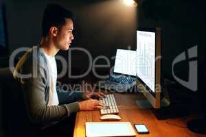 Long hours dont bother him at all. Shot of a handsome young male programmer working late in his office.