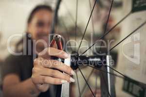 Were focused on quality rather than speed. Shot of an unrecognizable woman standing alone in her shop and repairing a bicycle wheel.