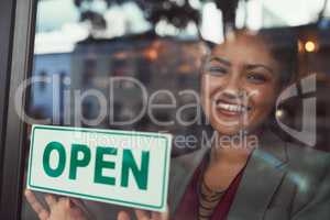 Shes eager to welcome all her customers. Portrait of a young business owner hanging up an open sign on the window of her cafe.