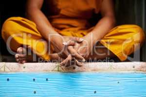 Living life simply. Shot of an unidentifiable buddhist monk sitting in the doorway of his home.