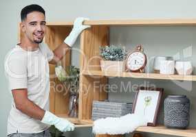 Dont give dust the chance to make itself at home. Shot of a young man dusting a shelf at home.