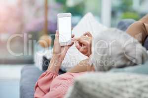 This is how Im spending my weekend. Rearview shot of a mature woman using her cellphone while relaxing on a sofa at home.