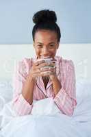 Her smile makes a every morning a little brighter. Shot of an attractive young woman enjoying her morning coffee in bed at home.
