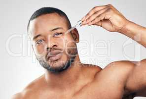 Use serum for a smoother, brighter complexion. Studio portrait of a handsome young man applying serum to his face with a dropper against a white background.