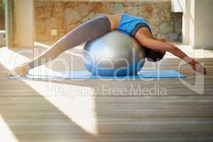 Toning the whole body throughout. Shot of a young woman practising yoga at home.