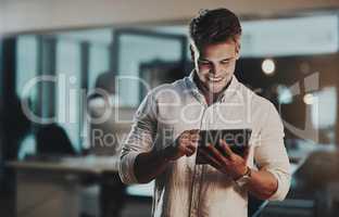 Nothing drives success like utmost commitment. Shot of a young businessman using a digital tablet in an office at night.