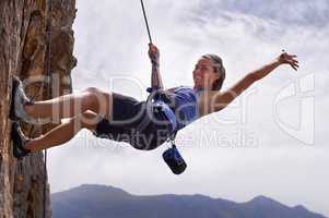 Nothing gets the heart going like scaling a rock face. Shot of a young woman hanging by a rope while rock climbing.