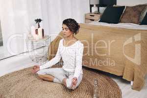 A cleanse of senses. Shot of an attractive young woman meditating on her bedroom floor at home.