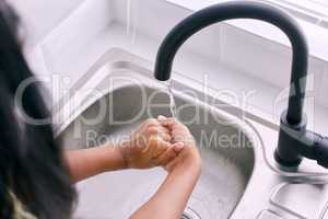 Clean hands= A healthier you. Cropped shot of an unrecognizable girl washing her hands by the kitchen sink.