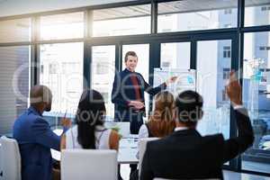Hes always open to questions. Shot of a young businessman giving a demonstration on a white board to his colleagues in a modern office.