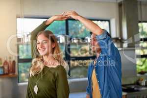 Dancing to the soundtrack of their life. Shot of an affectionate young couple dancing hand in hand together in their kitchen.