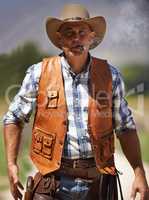 Hes the wrangler of beasts. A mature cowboy outdoors with his gun drawn.