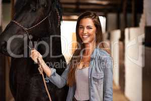 Hey girl, why. Portrait of a young woman in a stable with her horse.