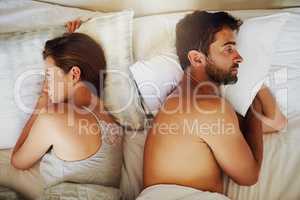 This is what weve become.... High angle shot of an arguing couple with their backs turned on each other in bed.