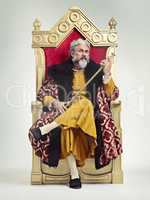 Throne of the kings. Studio shot of a richly garbed king sitting on a throne holding his scepter.